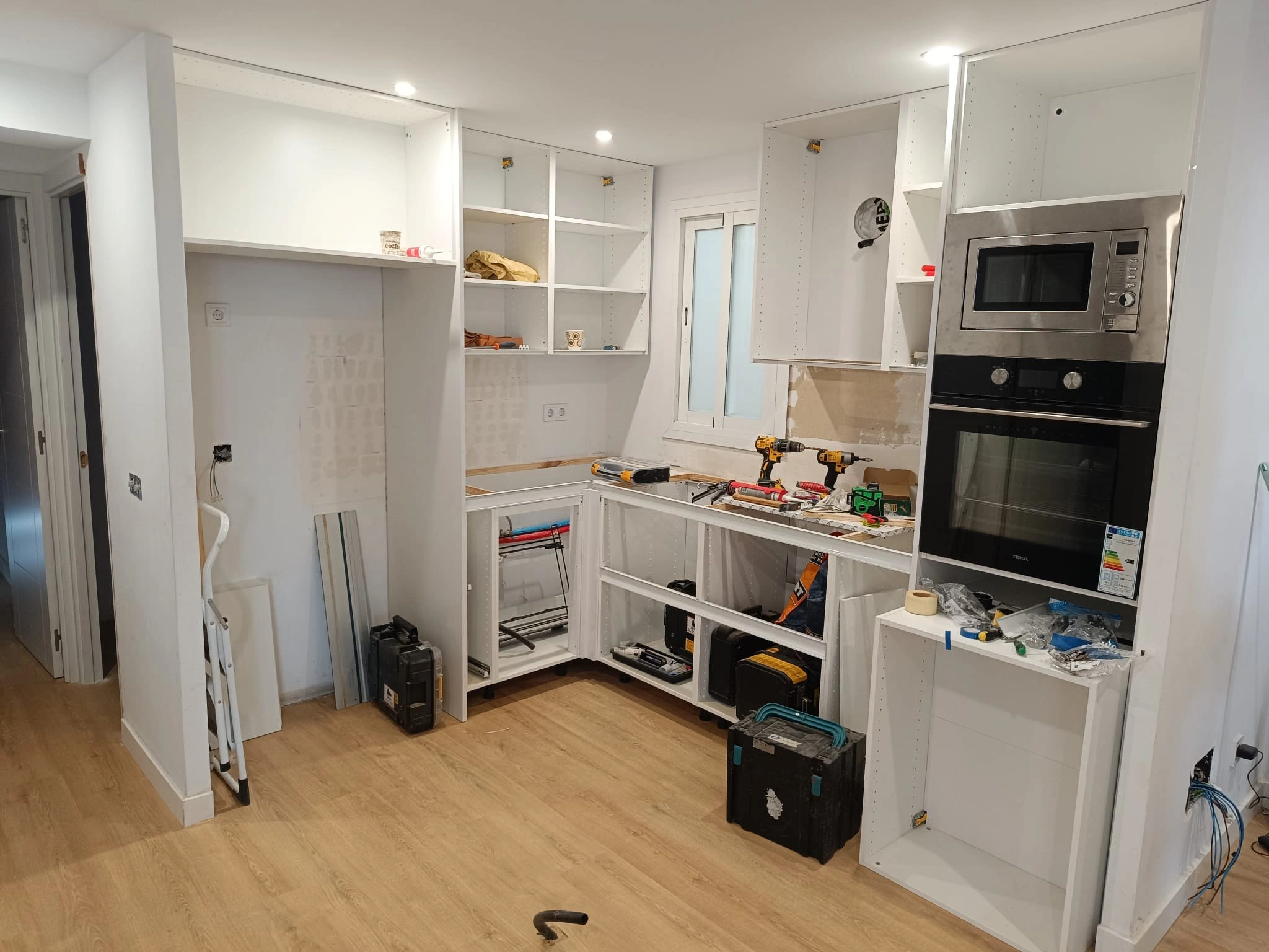 Cocina en obra, todavía sin isla: los muebles bajos elevados sobre perfiles de madera para ajustar las proporciones del cierre a techo