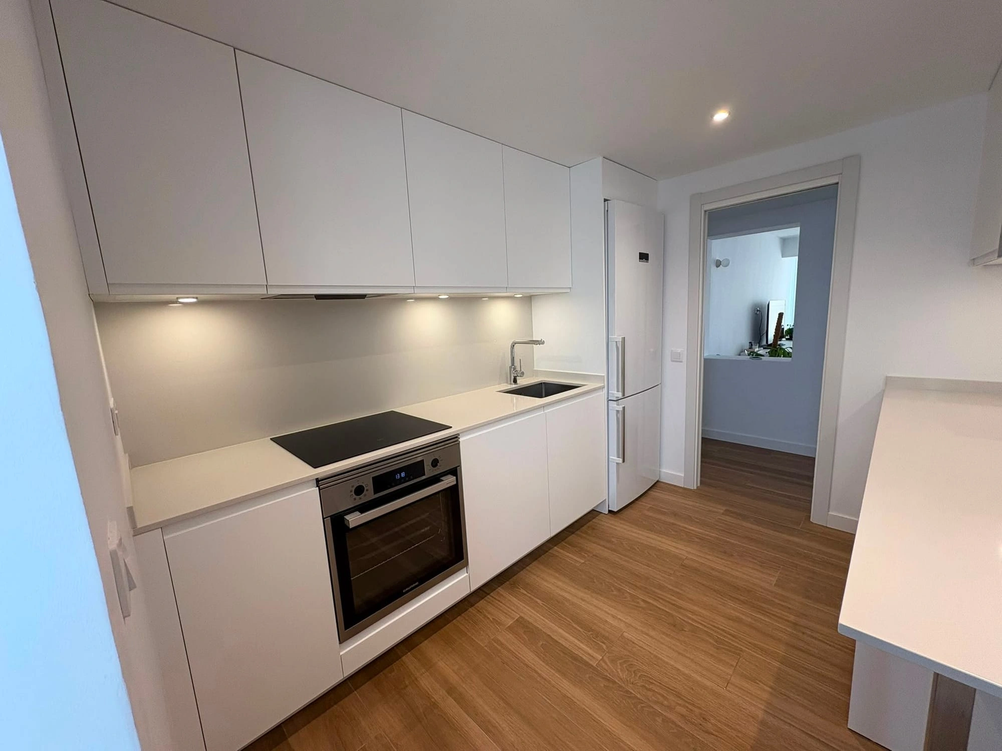 Renovated kitchen in Palma: new two-run layout with clear circulation, hob with oven underneath, sink and fridge integrated into the run